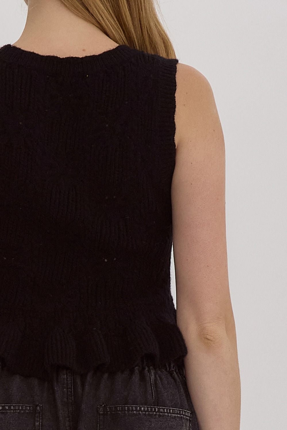 Solid knit scoop neck sleeveless cropped top w/ Ruffle hem. Bow detail at front