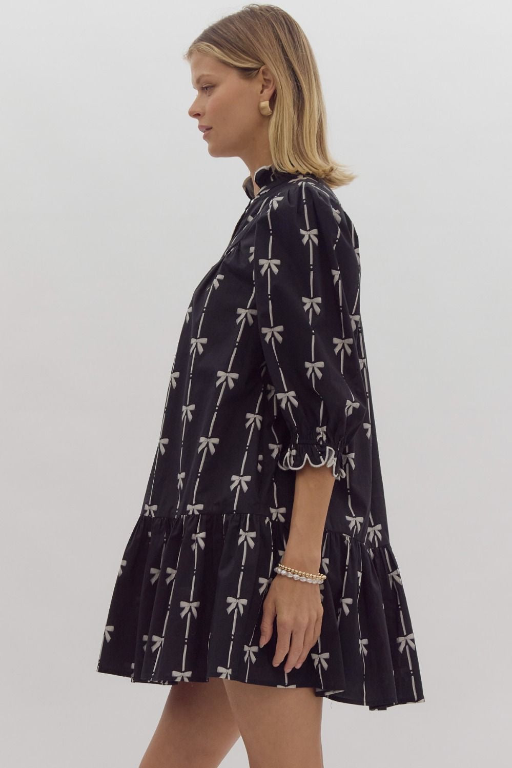 Bow print 3/4 sleeve v neck mini dress w/ button up detail at bust. Ruffled detail at cuff & neckline pockets