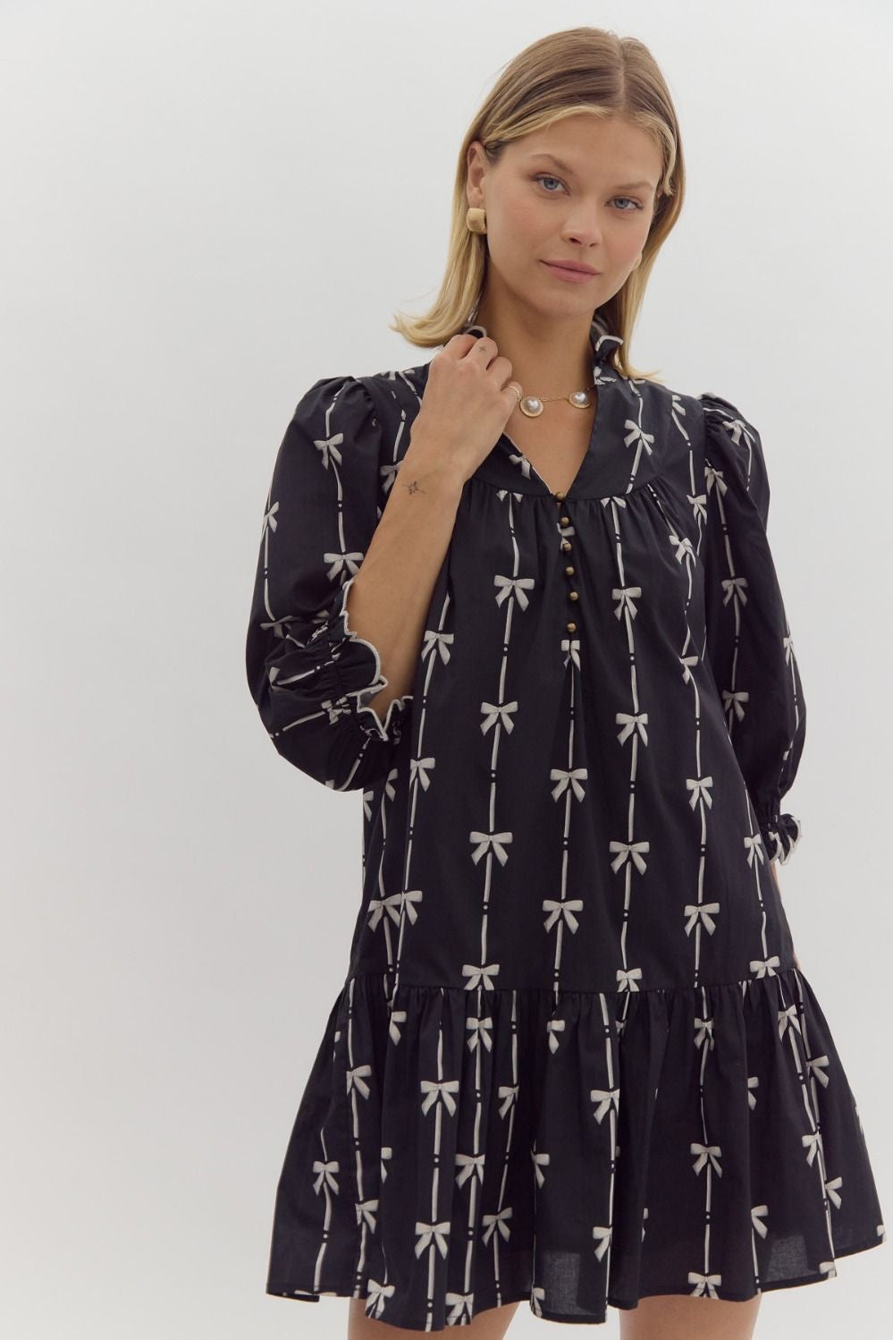 Bow print 3/4 sleeve v neck mini dress w/ button up detail at bust. Ruffled detail at cuff & neckline pockets