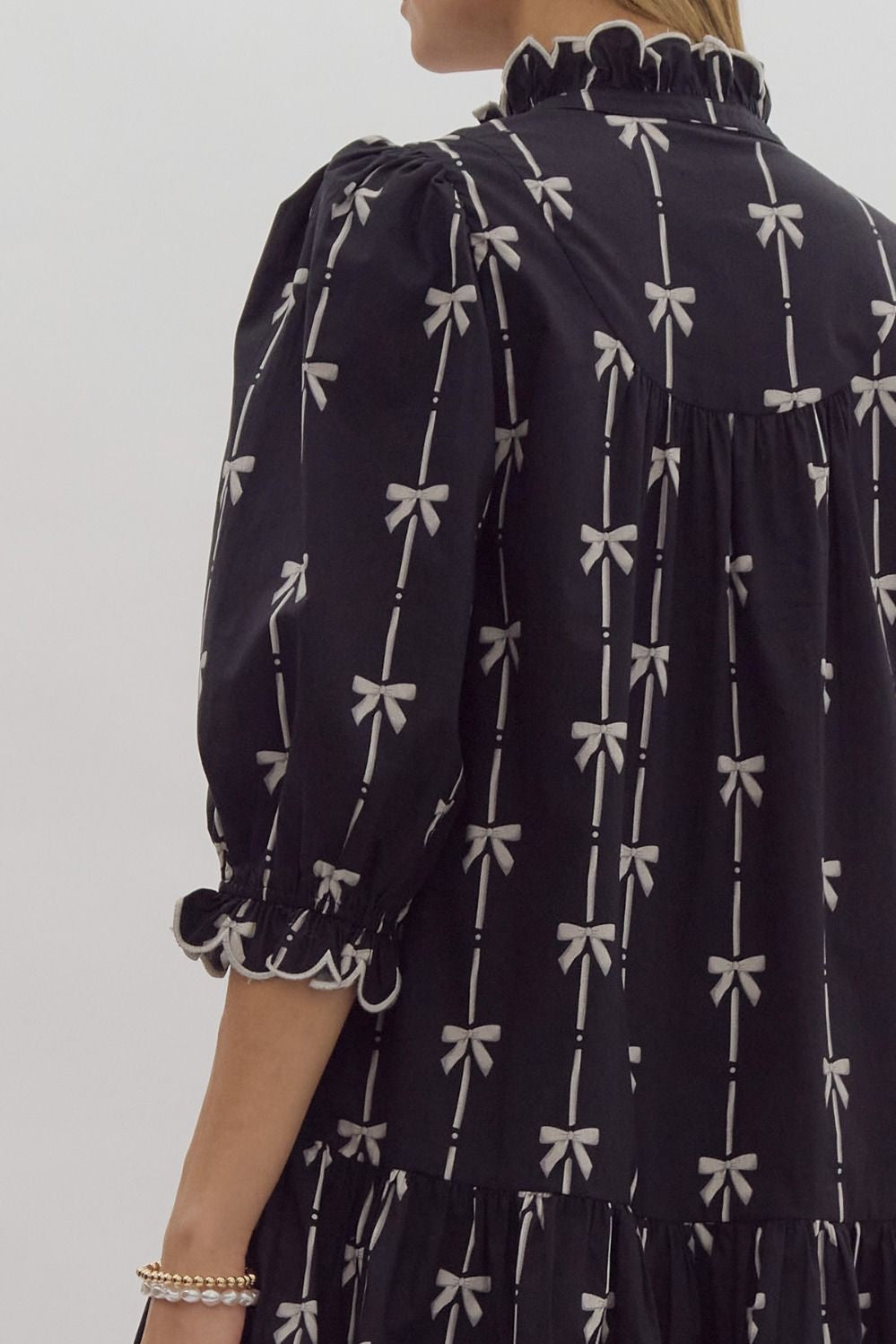 Bow print 3/4 sleeve v neck mini dress w/ button up detail at bust. Ruffled detail at cuff & neckline pockets