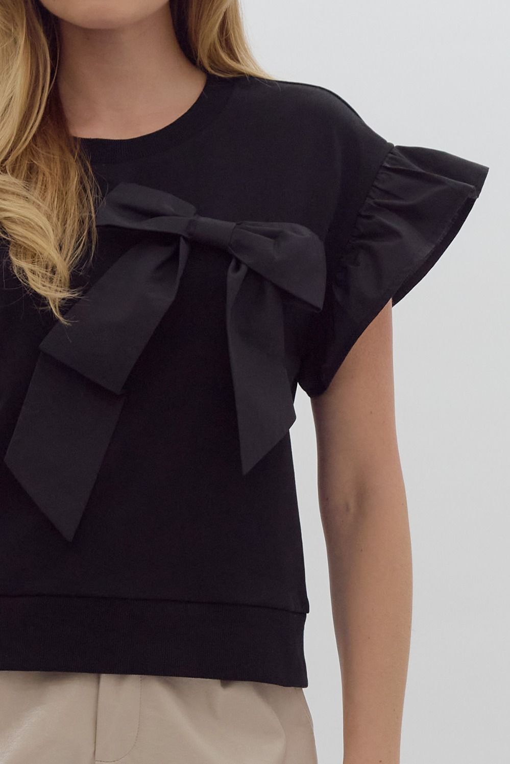 Solid short sleeve round neck top w/ ruffled sleeves. Ribbon detail @ bust.