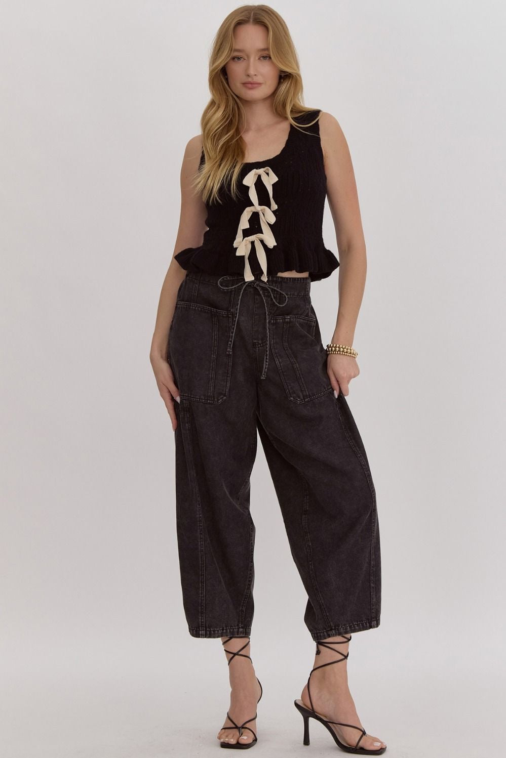 Solid knit scoop neck sleeveless cropped top w/ Ruffle hem. Bow detail at front
