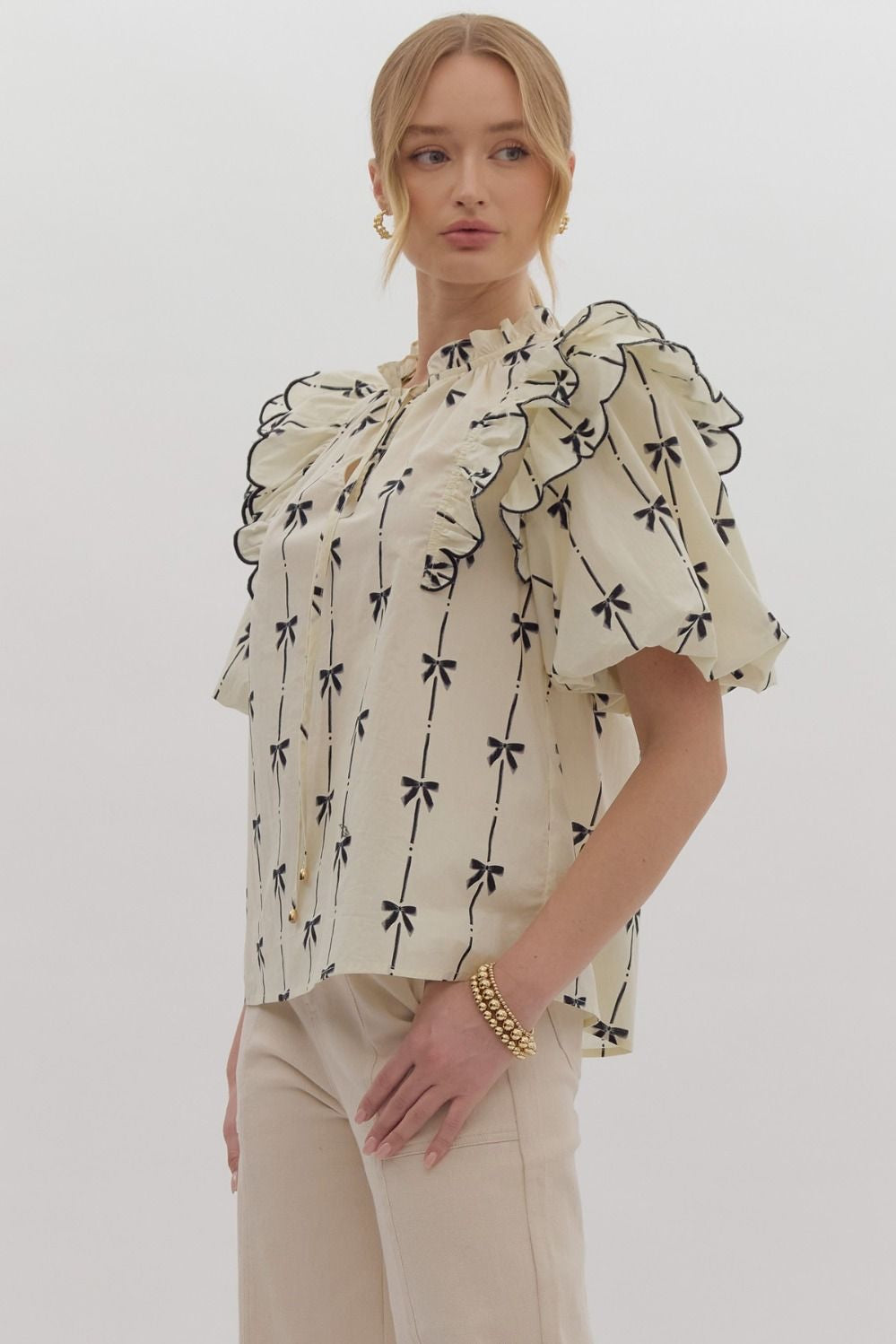 Bow print short puff sleeve v-neck top w/ tiered scallop delay at shoulders. Ruffle neckline